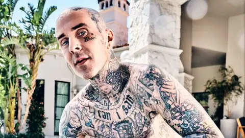 Travis Barker posing topless at home in LA tattoos 