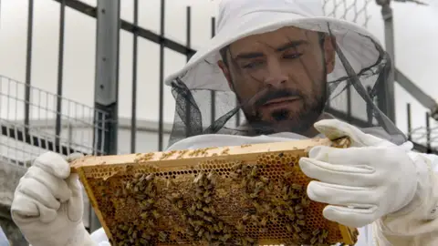 Zac Efron beekeeping suit with bees in down to earth documentary series netflix