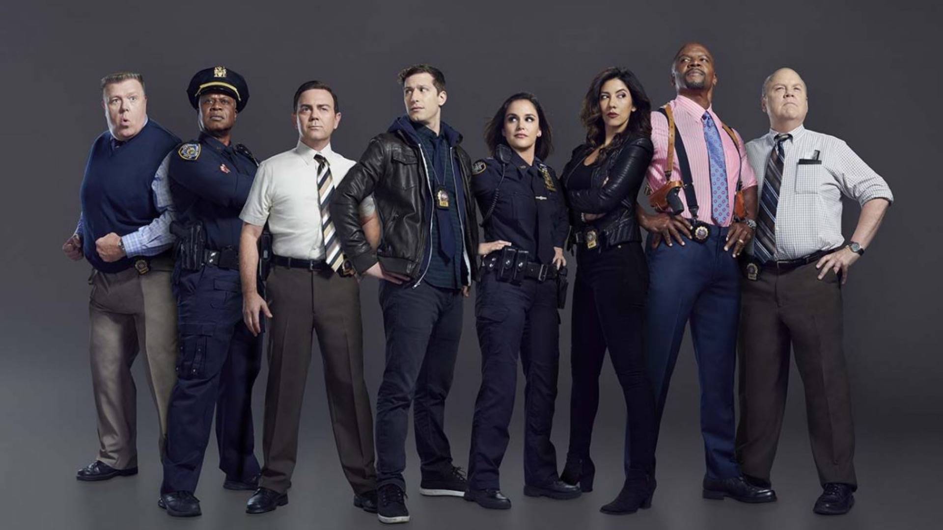 Cast Of Brooklyn 99 Posing In Front Of Dark Grey Background