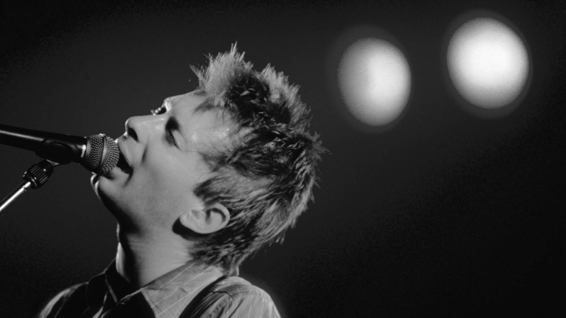 Thom Yorke singing into the microphone on stage in 1995