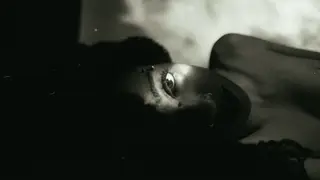 R&B artist Liv.e lies horizontally with her left eye illuminated by a bright light. 
