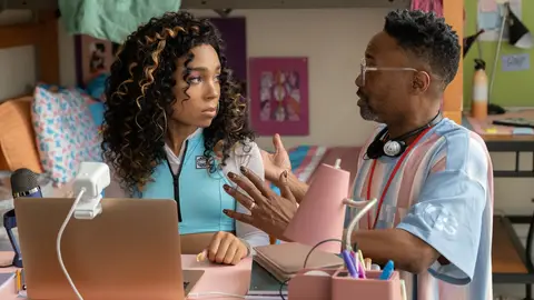 Eva Reigns sitting on a desk facing Billy Porter in her character's bedroom as Billy Porter's character speaks to her in the film Anything's Possible.