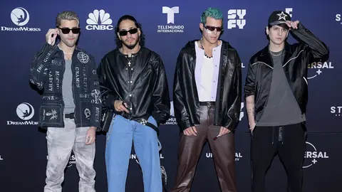 CNCO pose in front of a step and repeat background