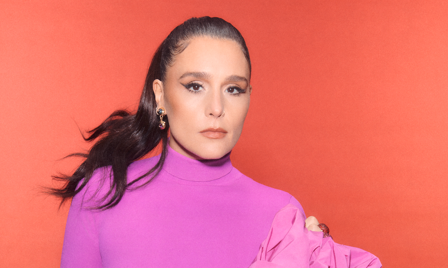 Jessie Ware poses in purple against a peach background