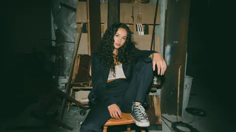 Singer YDE poses in an armchair with one leg up.