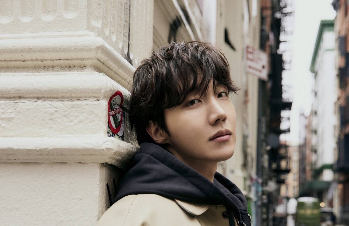 J-Hope poses in front of a building on a street
