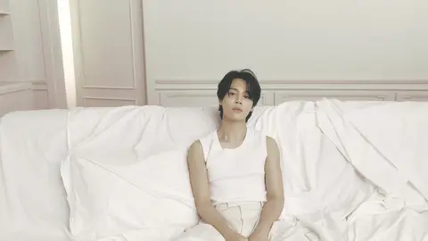 Jimin poses in white on an all-white sofa with white walls behind him