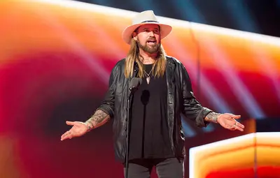 Billy Ray Cyrus dons a leather jacket and his signature cowboy hat.