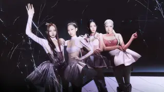K-pop girl group Blackpink pose in a darkened room.