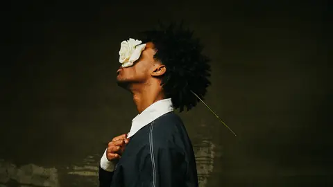The artist D4vd holds a white flower over his face.