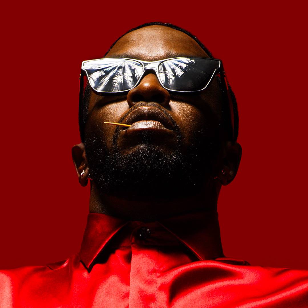 Diddy in sunglasses against a red background.