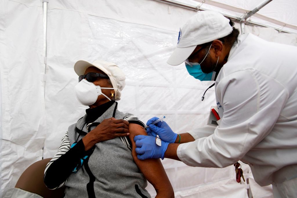 Dr. Jerry P. Abraham administers a Covid-19 vaccination to a senior citizen in a vaccination tent at the Kedren Community Health Center on January 25, 2021 in Los Angeles, California. - While vaccination priority is given to people including healthcare workers and the elderly, some outside the priority tiers are waiting in line to potentially receive a dose that needs to be administered before it expires and goes to waste. (Photo by Patrick T. FALLON / AFP) (Photo by PATRICK T. FALLON/AFP via Getty Images)