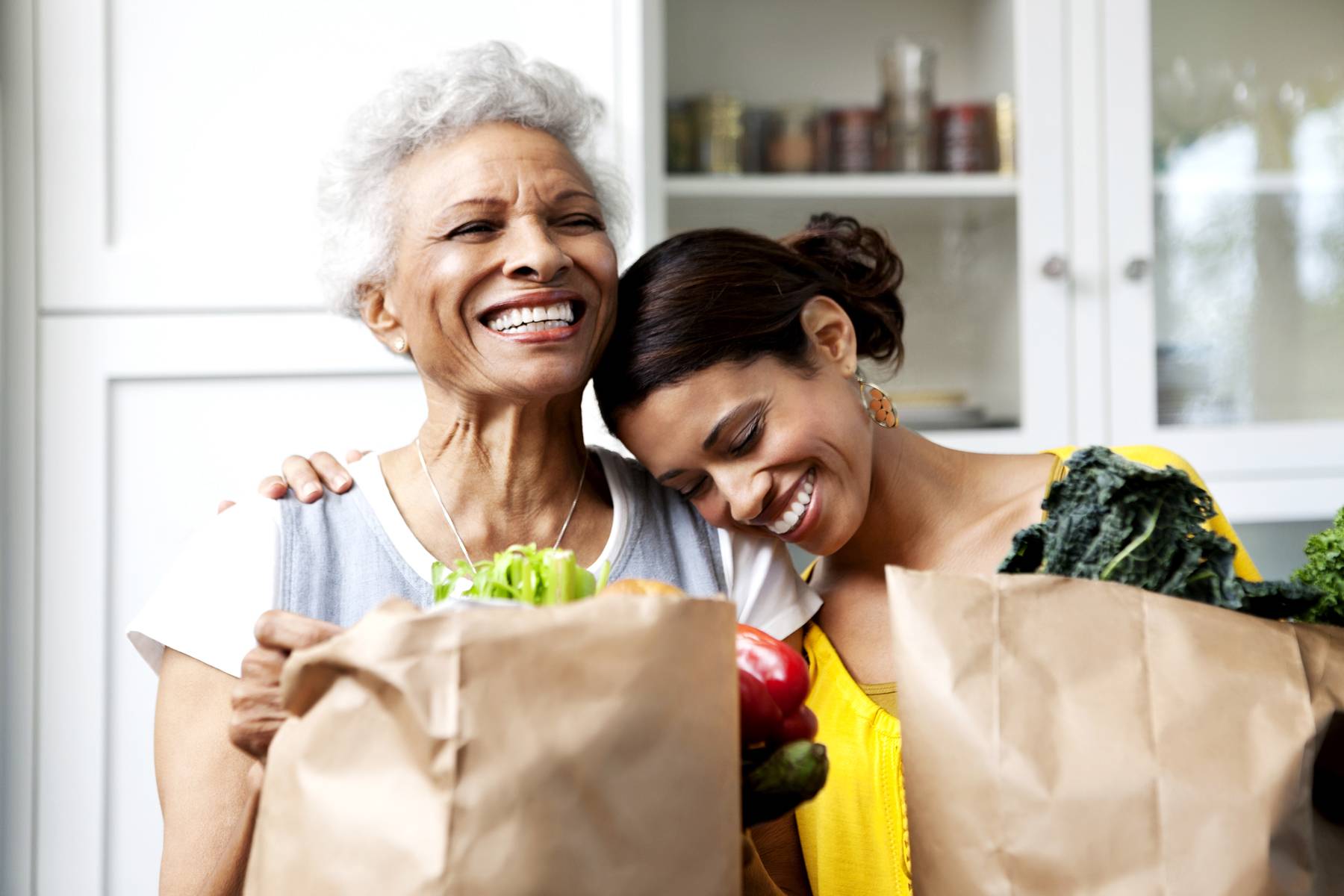 Mother and daughter unpacking groceries in kitchen 