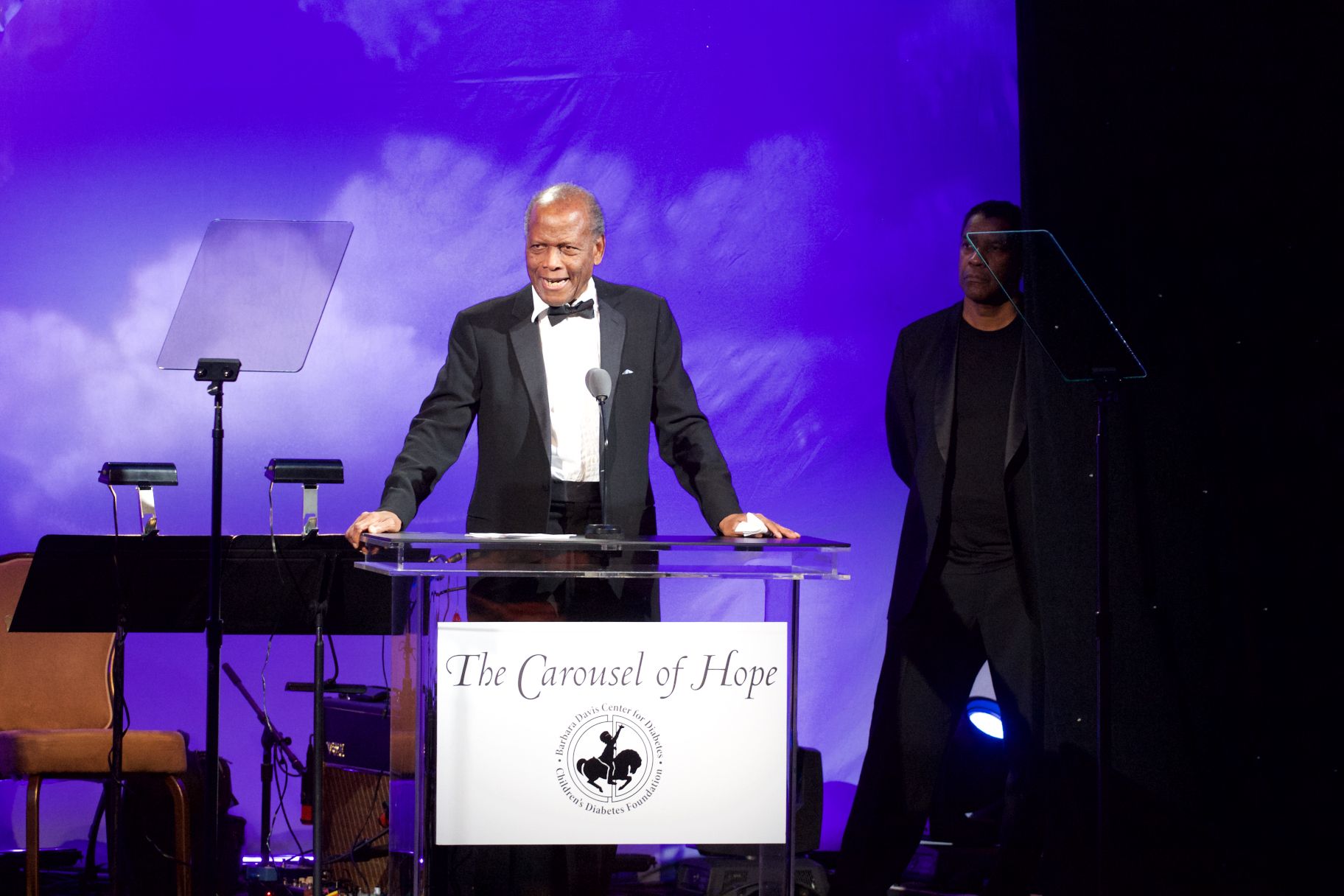 BEVERLY HILLS, CA - OCTOBER 08:  (L-R) Inspirational Lifetime Achievement Award Recipient Sidney Poitier speaks onstage as  Actor Denzel Washington looks on at the 2016 Carousel Of Hope Ball  at The Beverly Hilton Hotel on October 8, 2016 in Beverly Hills, California.  (Photo by Earl Gibson III/WireImage)