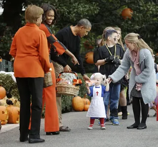 A Living Doll - The first lady admires this tiny trick-or-treater's costume.(Photo: AP Photo/Pablo Martinez Monsivais)