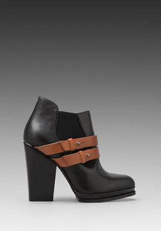 A Little Contrast - We love how the cognac buckle detailing on these Ivey booties by Kelsi Dagger add interest and contrast against a classic shape. &nbsp;   (Photo: Revolve Clothing)