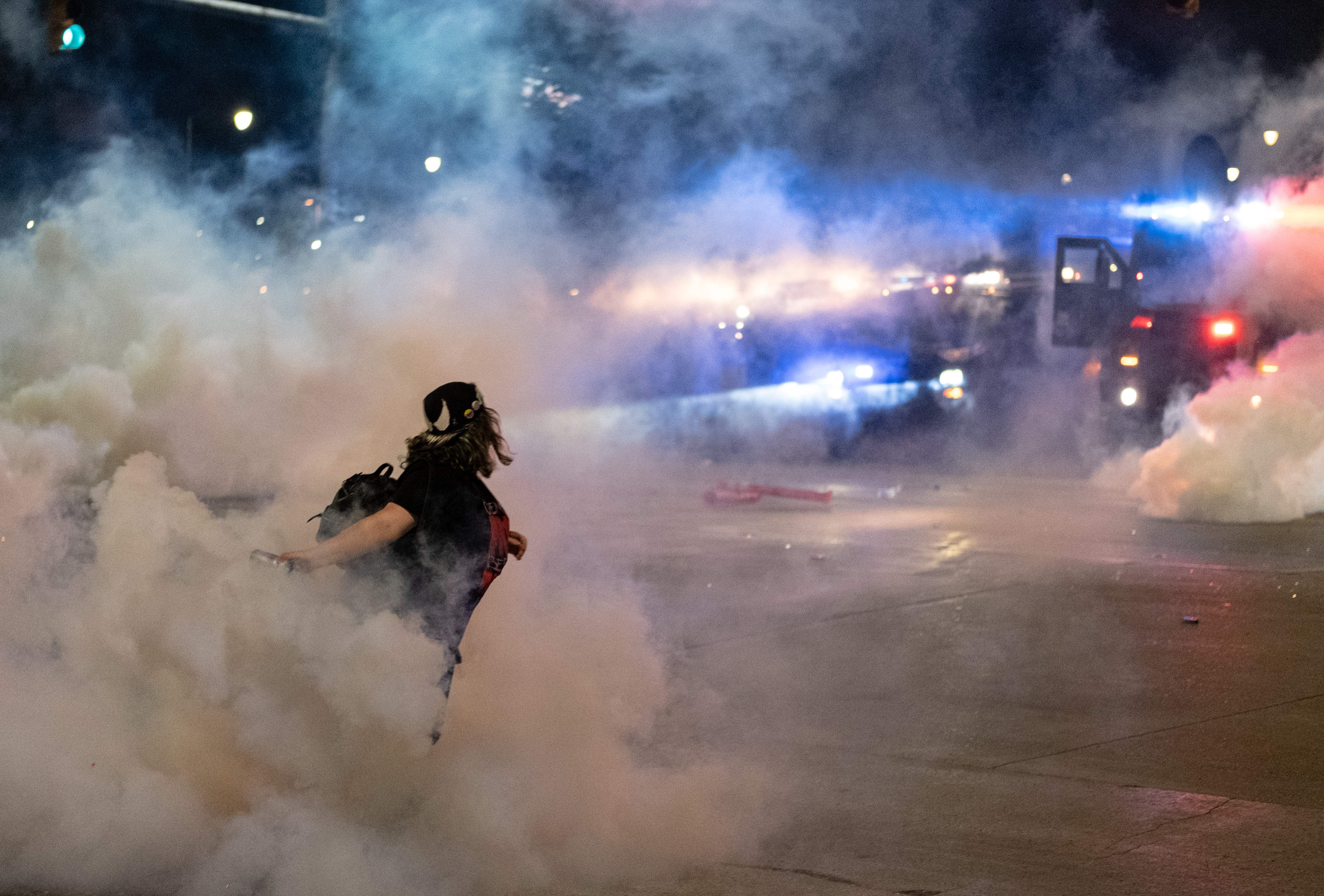 TOPSHOT - A protester hurls a tear gas canister back towards the Detroit police after tensions were sparked by arrests of protesters, through the streets of Detroit, Michigan for a second night May 30,2020 to protest the killing of George Floyd who was killed by a white officer who held his knee on his neck for several minutes. - Curfews were imposed on major US cities as clashes over police brutality erupted across America with demonstrators ignoring warnings from President Donald Trump that his government would stop the violent protests "cold." (Photo by SETH HERALD / AFP) (Photo by SETH HERALD/AFP via Getty Images)