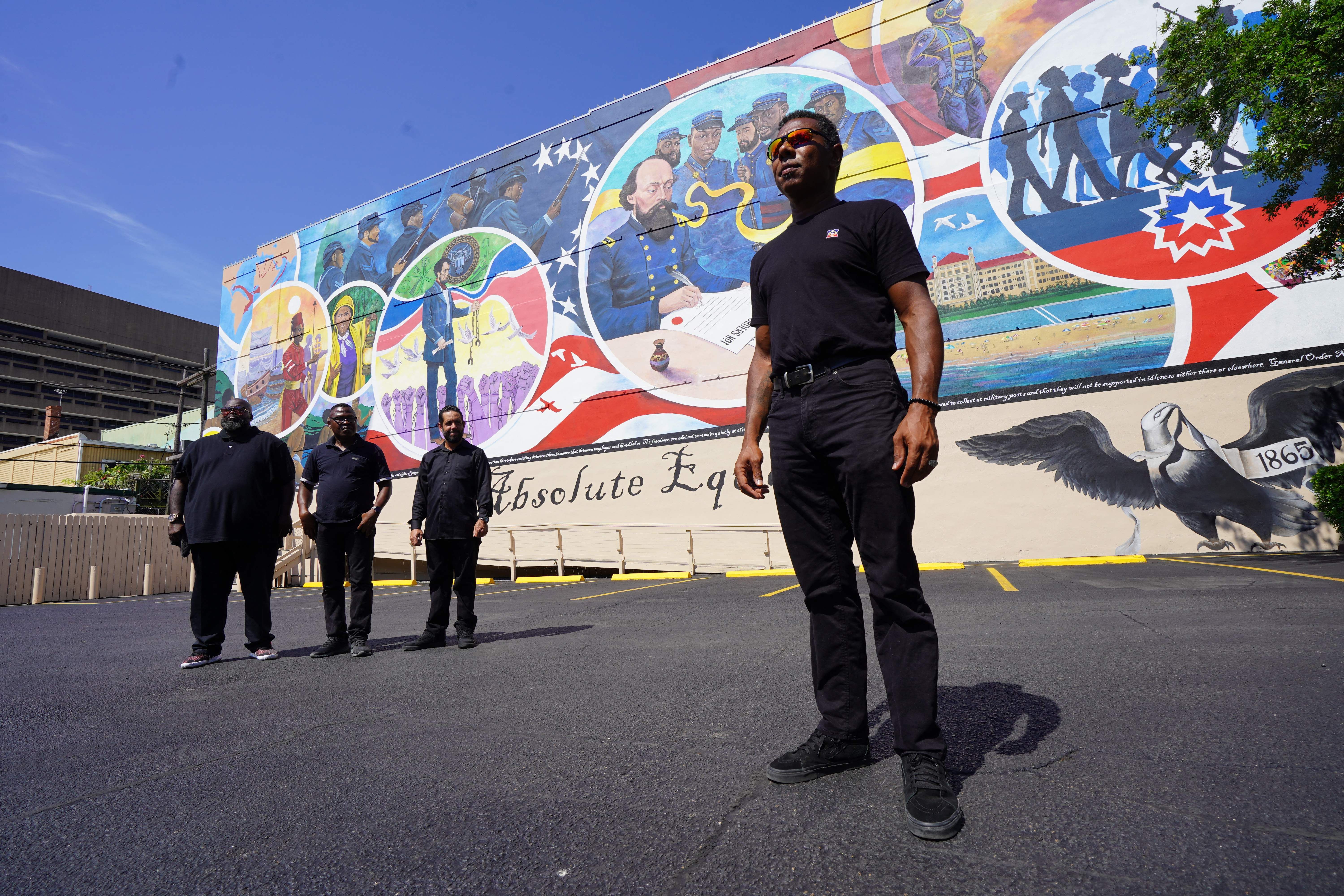 (L-R) Artists Dantrel Boone, Samson Adenugba, Joshua Bennett, and principal artist Reginald C. Adams pose in front of their "Absolute Equality" mural in Galveston, Texas, on June 16, 2021. - The mural is to be dedicated on June 19, now the Juneteenth National Independence Day national holiday, to celebrate the day in Galveston in 1865 when the last enslaved African Americans learned that they were free. - RESTRICTED TO EDITORIAL USE - MANDATORY MENTION OF THE ARTIST UPON PUBLICATION - TO ILLUSTRATE THE EVENT AS SPECIFIED IN THE CAPTION (Photo by Francois PICARD / AFP) / RESTRICTED TO EDITORIAL USE - MANDATORY MENTION OF THE ARTIST UPON PUBLICATION - TO ILLUSTRATE THE EVENT AS SPECIFIED IN THE CAPTION / RESTRICTED TO EDITORIAL USE - MANDATORY MENTION OF THE ARTIST UPON PUBLICATION - TO ILLUSTRATE THE EVENT AS SPECIFIED IN THE CAPTION (Photo by FRANCOIS PICARD/AFP via Getty Images)