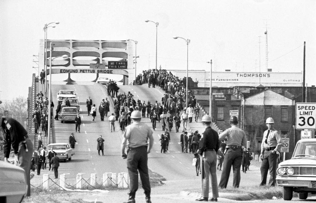 State troopers watch as marchers cross the Edmund Pettus Bridge over the Alabama River in Selma, Alabama as part of a civil rights march on March 9. Two days before troopers used excessive force driving marchers back across the bridge, killing one protester.