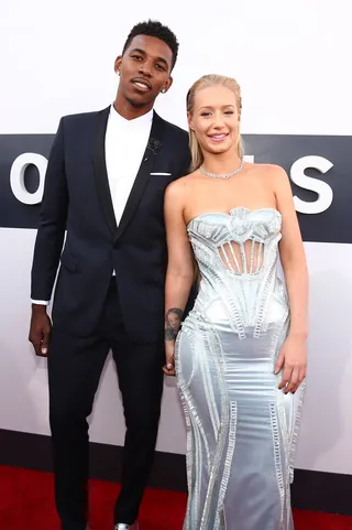 Disco Ball - Iggy shines at the 2014 MTV Video Music Awards in a heavily-embellished custom silver gown from Versace. Nick rocked a slim-lapeled navy blue tux with reflective silver shoes that matched his girl’s gown.&nbsp; (Photo: Christopher Polk/Getty Images for MTV)