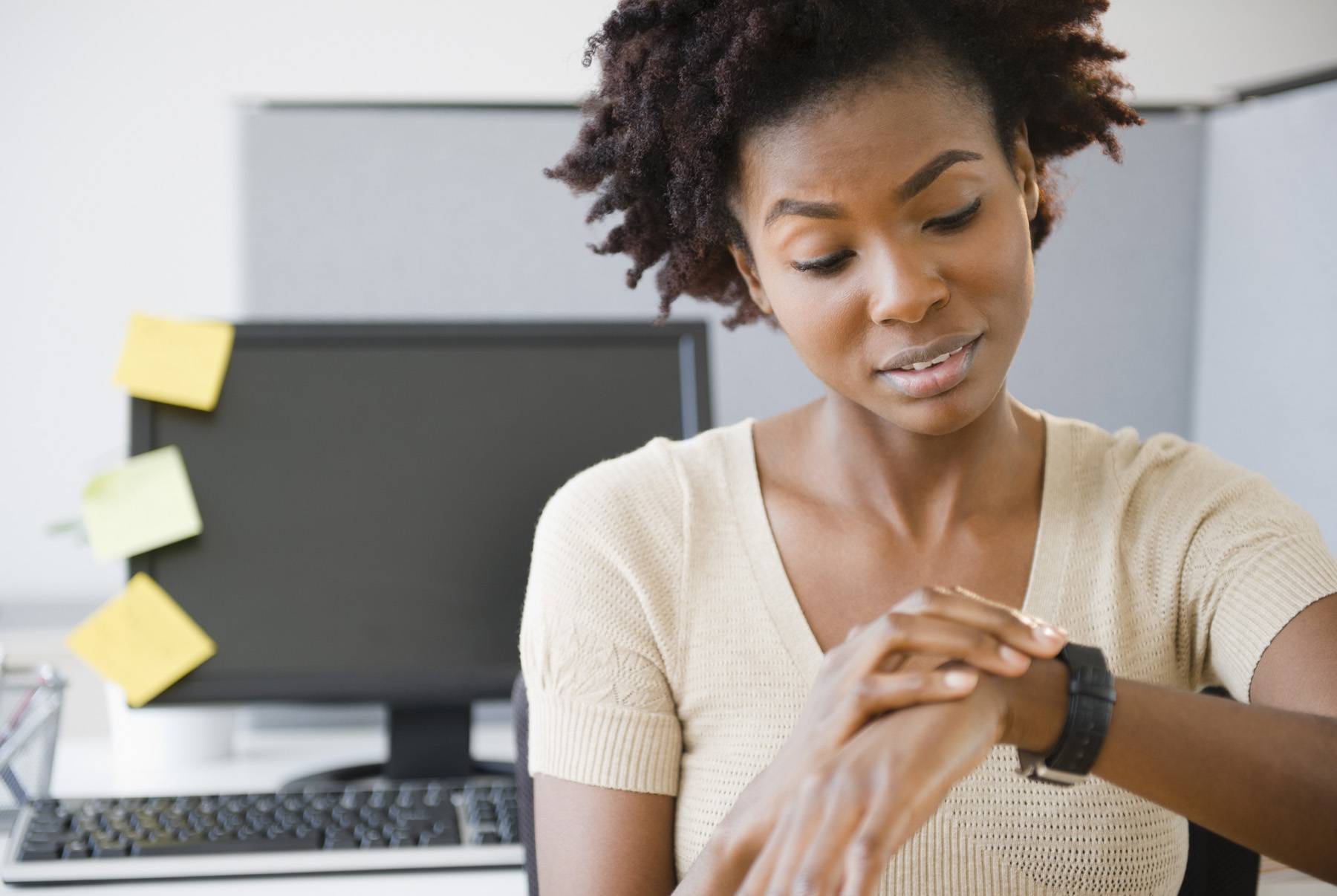 businesswoman checking the time on her watch, at her desk