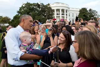 It Never Gets Old - Holding babies is all part of the job. Here the president checks out one's foot while greeting guests at a picnic on the South Lawn of the White House.  (Photo: Official White House Photo by Pete Souza)