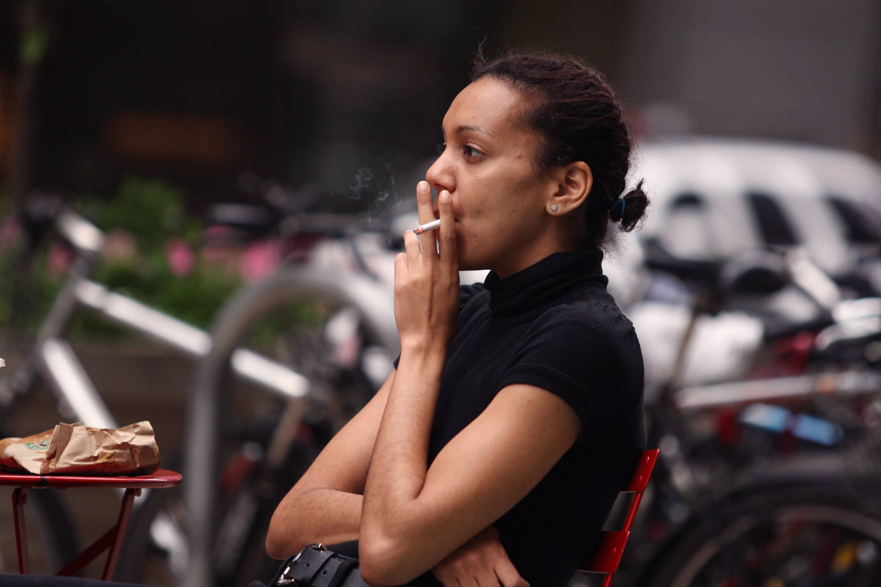 woman smoking cigarette outside city