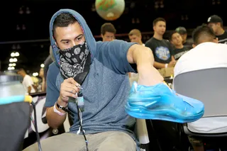 Custom Kicks - An artist airbrushes and customizes a pair of sneakers with an ice blue glaze.(Photo: Rachel Murray/Getty Images for BET)