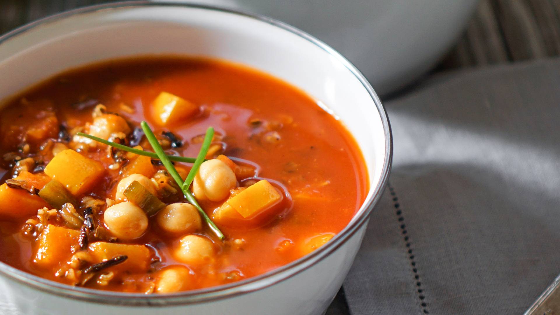 Vegetarian tasty spicy chili chick pea pumpkin wild rice soup pozole stew bowl on a wooden background