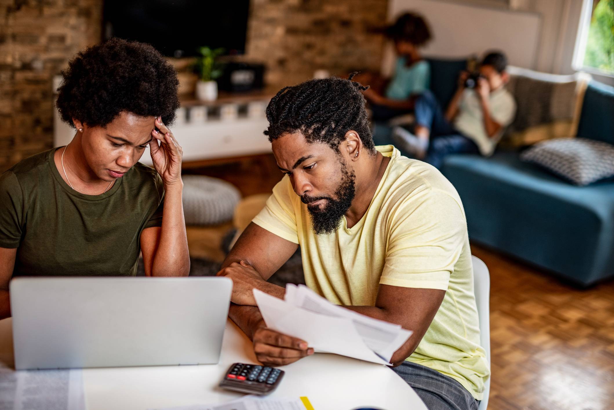 A Black couple sitting at the table paying bills. 