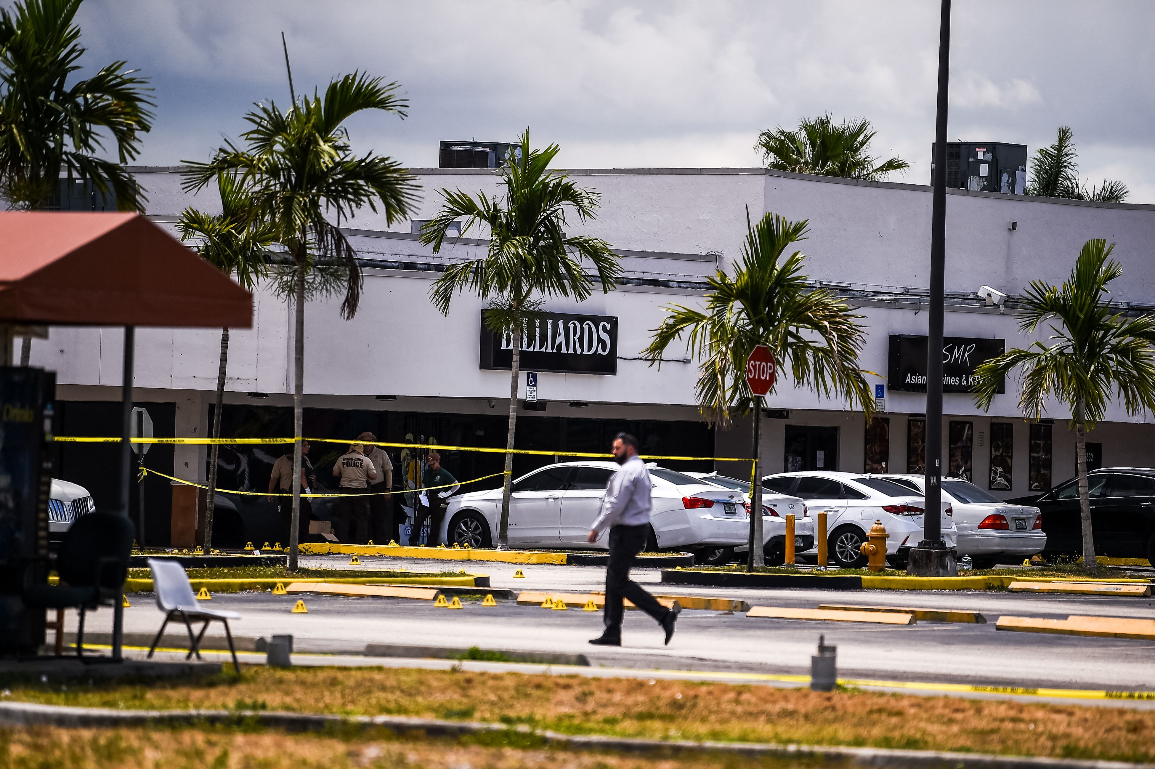 Miami Dade police officers collect evidence from the parking lot in front of Billiard's club that was rented for a concert, after three gunmen killed two people and injured 20 overnight in the Hialeah area of Miami Dade county on May 30 2021. - Two people were killed and at least 20 injured Sunday when three shooters fired indiscriminately into a crowd outside a concert in Miami, Florida, local police said. Gunfire erupted during the early hours outside a billiards hall in a row of businesses near Miami Gardens, northwest of the coastal city's downtown. People crowded the venue, which was "hosting a scheduled event and several patrons were standing outside," Miami-Dade Police Department said in a statement. (Photo by CHANDAN KHANNA / AFP) (Photo by CHANDAN KHANNA/AFP via Getty Images)