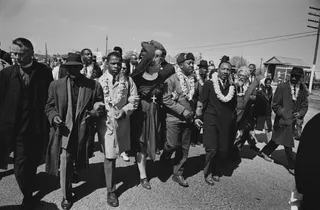 Marching with Dr. Martin Luther King Jr. - John Lewis marching arm in arm with Dr. Martin Luther King Jr., Reverend Ralph Abernathy, Ralph Bunche, Abraham Joshua Heschel, Fred Shuttlesworth, and more during a march in Selma, Alabama on March 21, 1965.