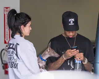 Upgrade You - A make-up free Kylie Jenner holds her dog Norman while her man-friend Tyga texts as they wait at a car dealership in Calabasas. (Photo: VIPix / Splash News)