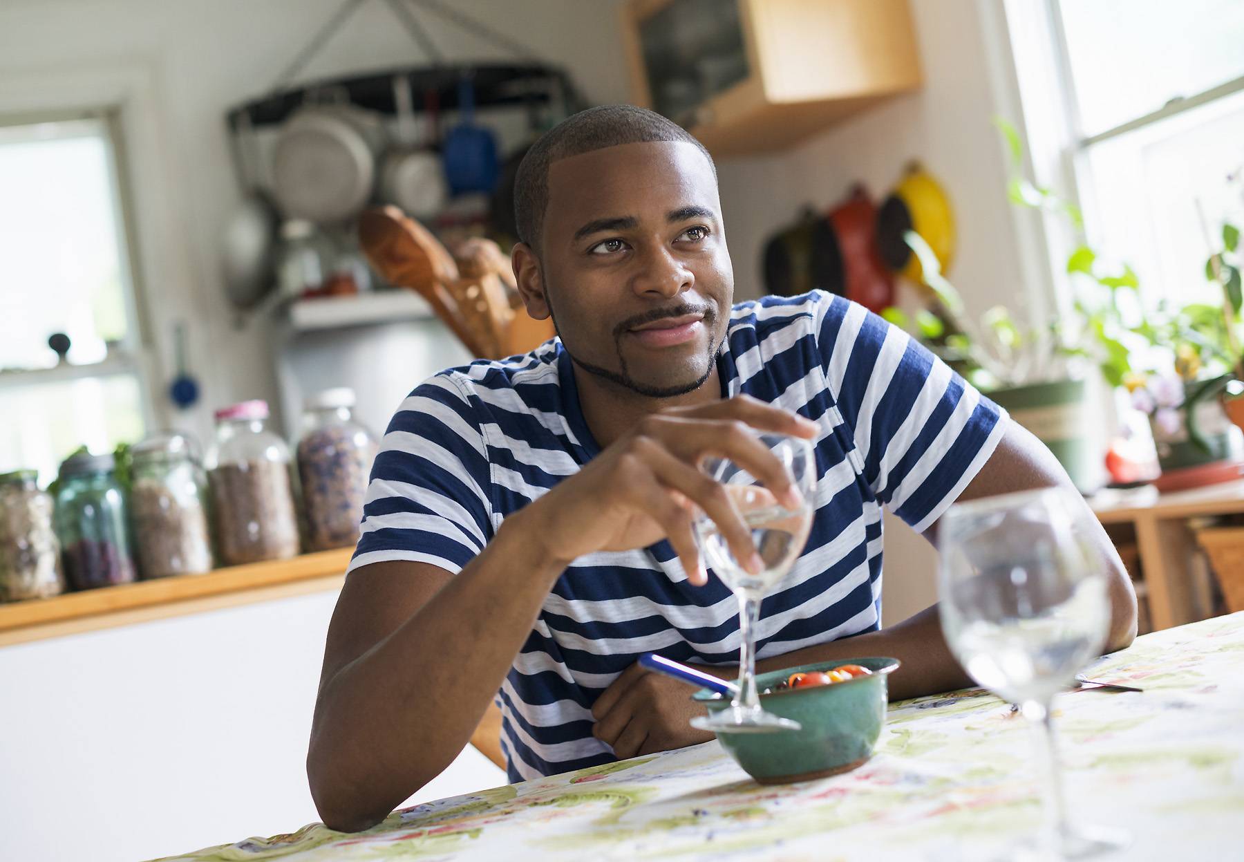 A man sitting at a table eating dessert,holding a glass of wine.