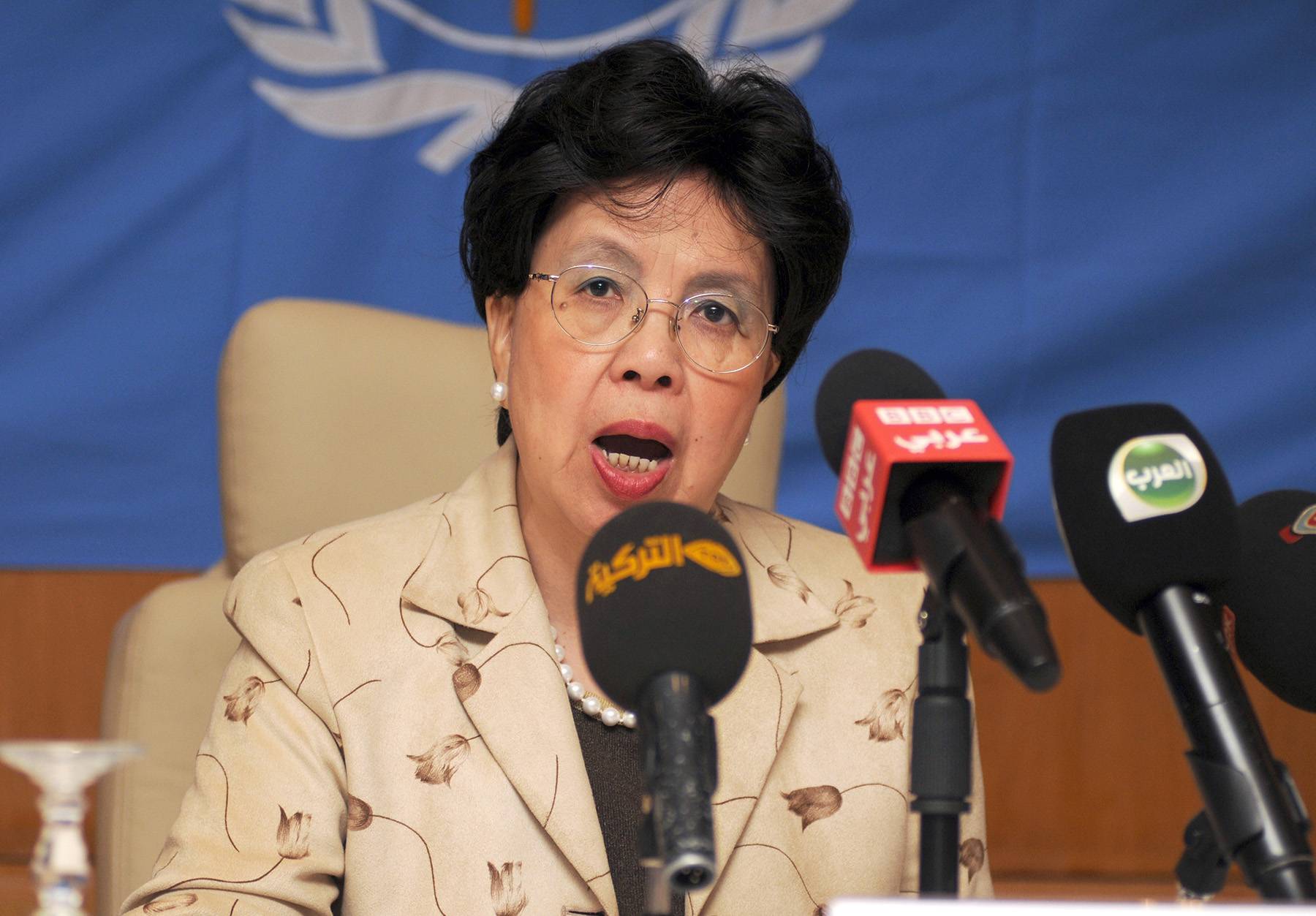 A woman with a tan suit siting in front of a microphone 