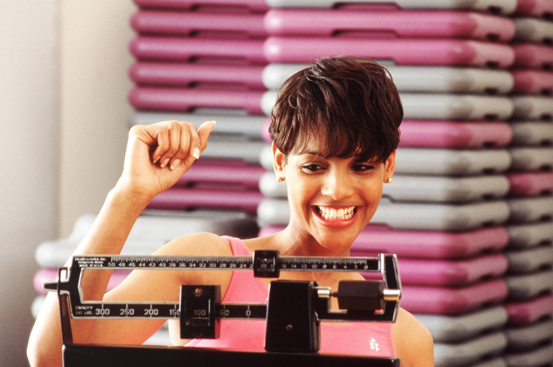 woman weighing herself in the gym