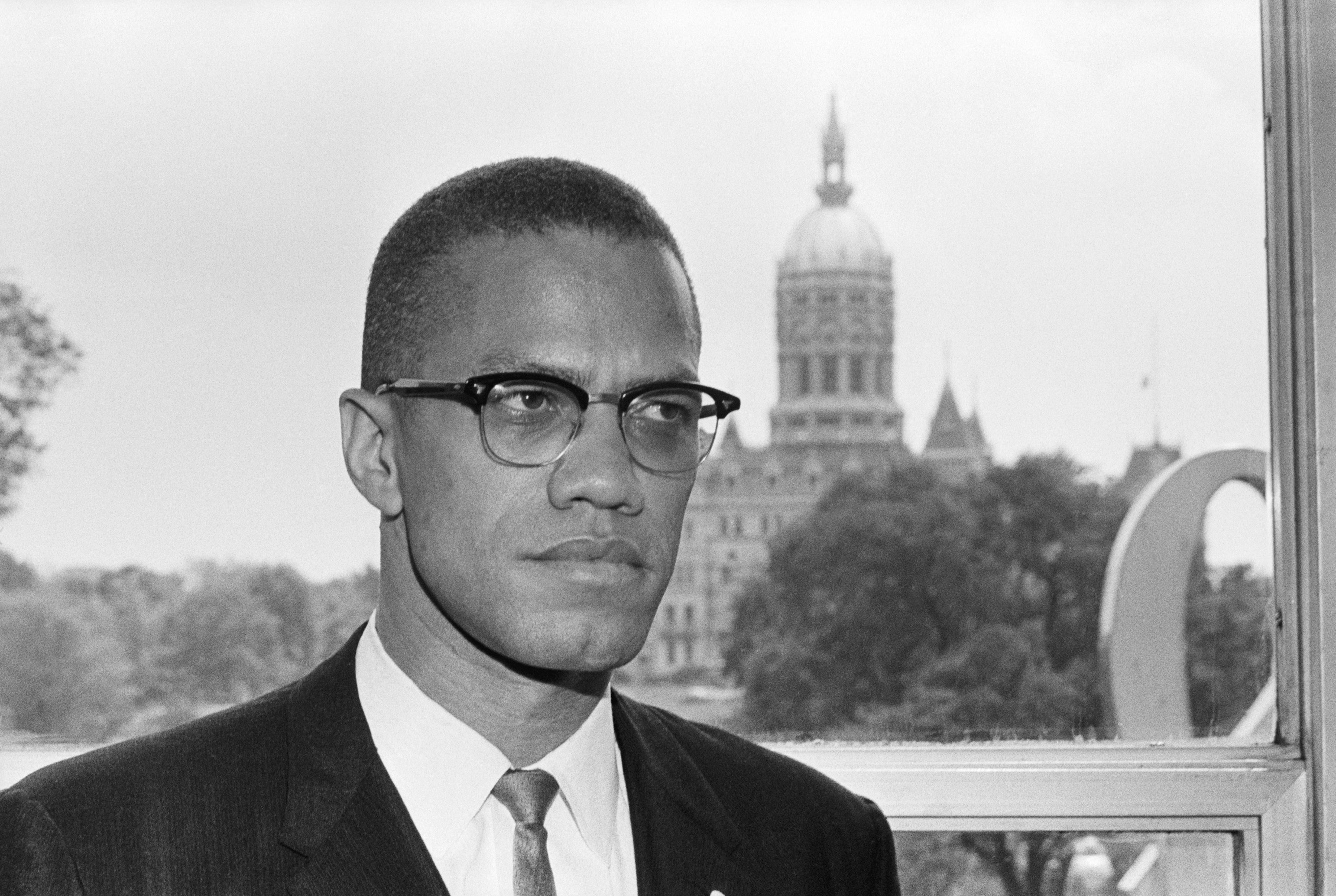 (Original Caption) 6/4/1963-Hartford, CT: Malcolm X, leading spokesman for the Black Muslim movement, is shown with the dome of the Connecticut Capitol behind him as he arrived in Hartford for a two day visit.