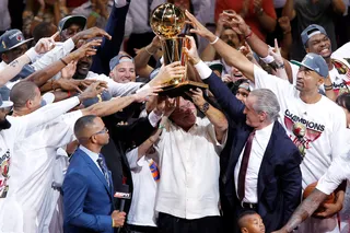 All In - Team owner Micky Arison and Miami Heat teammates hoist up the Larry O'Brien Championship trophy. (Photo: Mike Ehrmann/Getty Images)