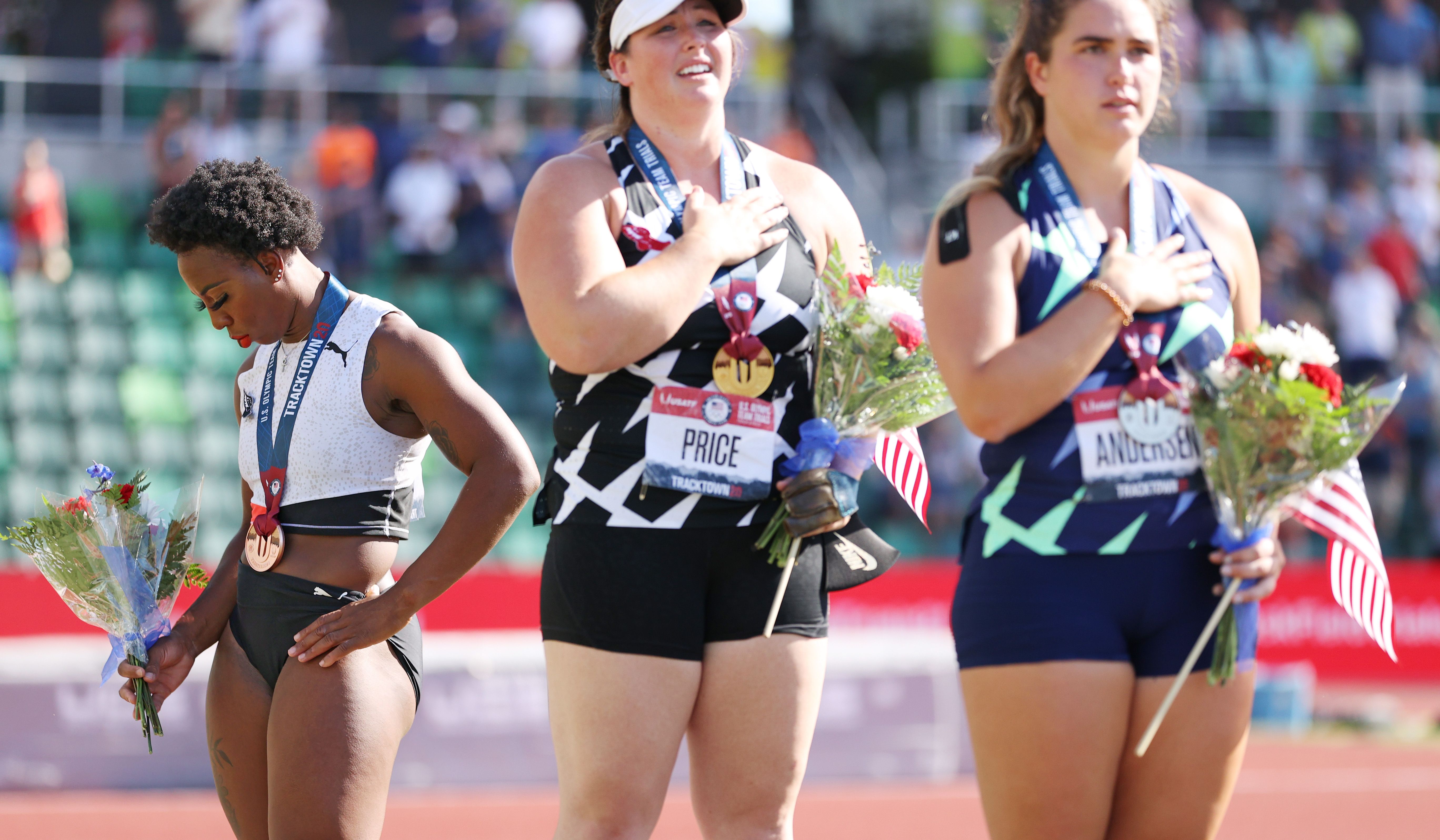 EUGENE, OREGON - JUNE 26: Gwendolyn Berry (L), third place, looks on during the playing of the national anthem with DeAnna Price (C), first place, and Brooke Andersen, second place, on the podium after the Women's Hammer Throw final on day nine of the 2020 U.S. Olympic Track & Field Team Trials at Hayward Field on June 26, 2021 in Eugene, Oregon. (Photo by Patrick Smith/Getty Images)