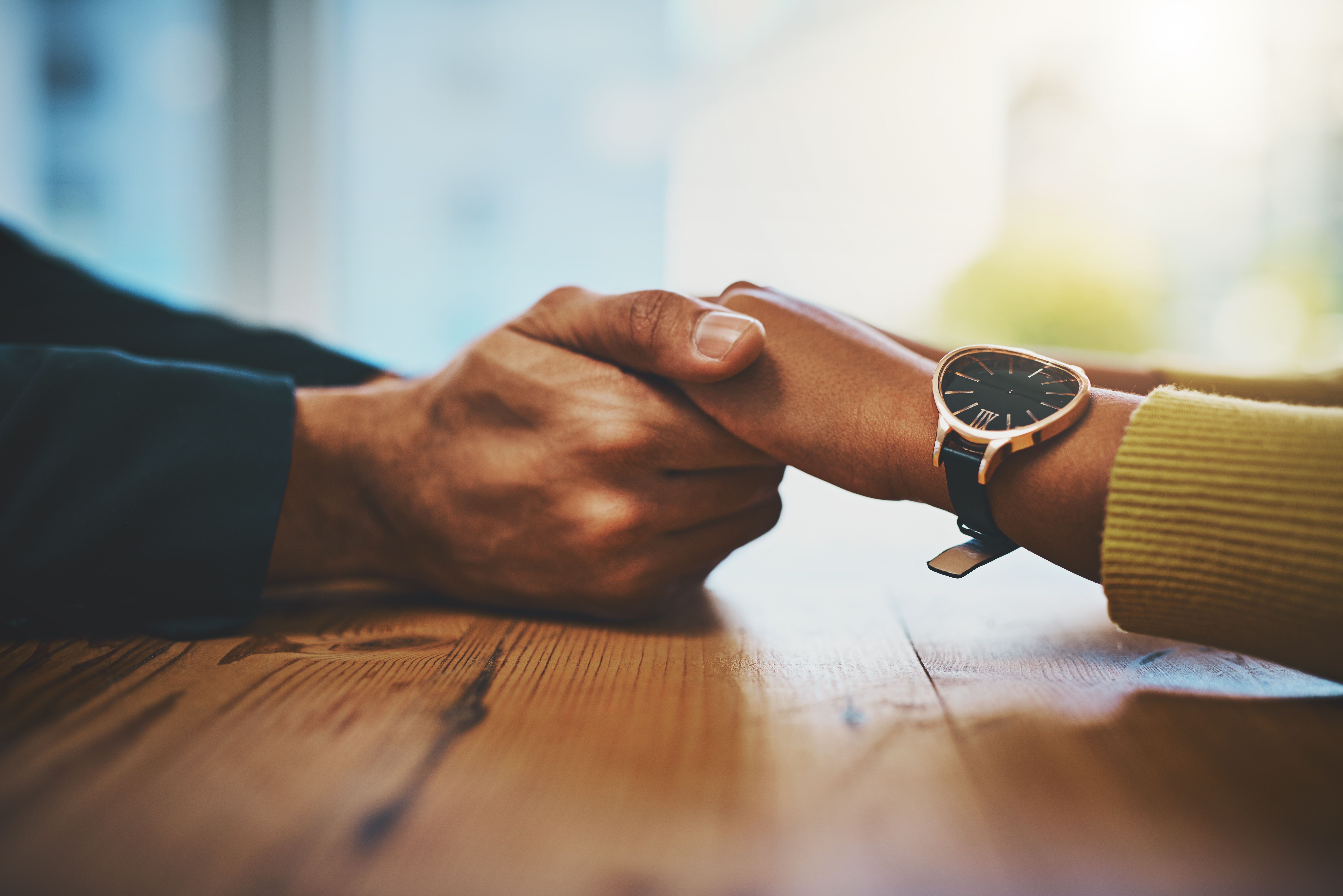 Cropped shot of a man and woman compassionately holding hands at a table
