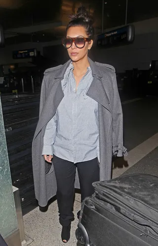 Hide and Seek - Pregnant reality star Kim Kardashian is seen hiding behind a large pair of sunglasses and wearing a loose fitting shirt and jacket while arriving at Los Angeles Airport after returning from Paris with her beau, Kanye West. (Photo: Revolution Pix, PacificCoastNews.com)