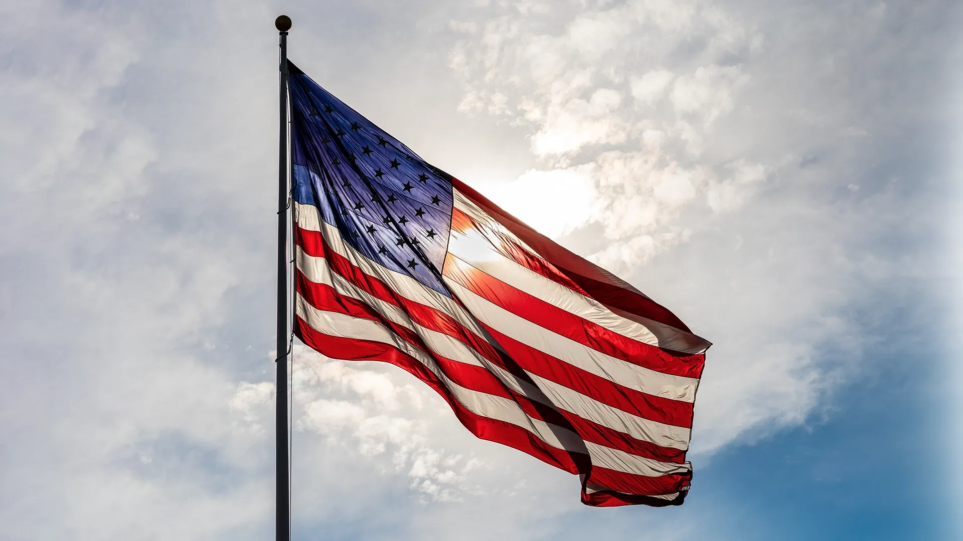 American flag in front of a sunny blue sky.