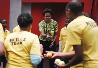 Another Game - The first lady passes a tennis ball as she plays a game with young people during the same South African event. (Photo: AP Photo/Charles Dharapak, Pool)