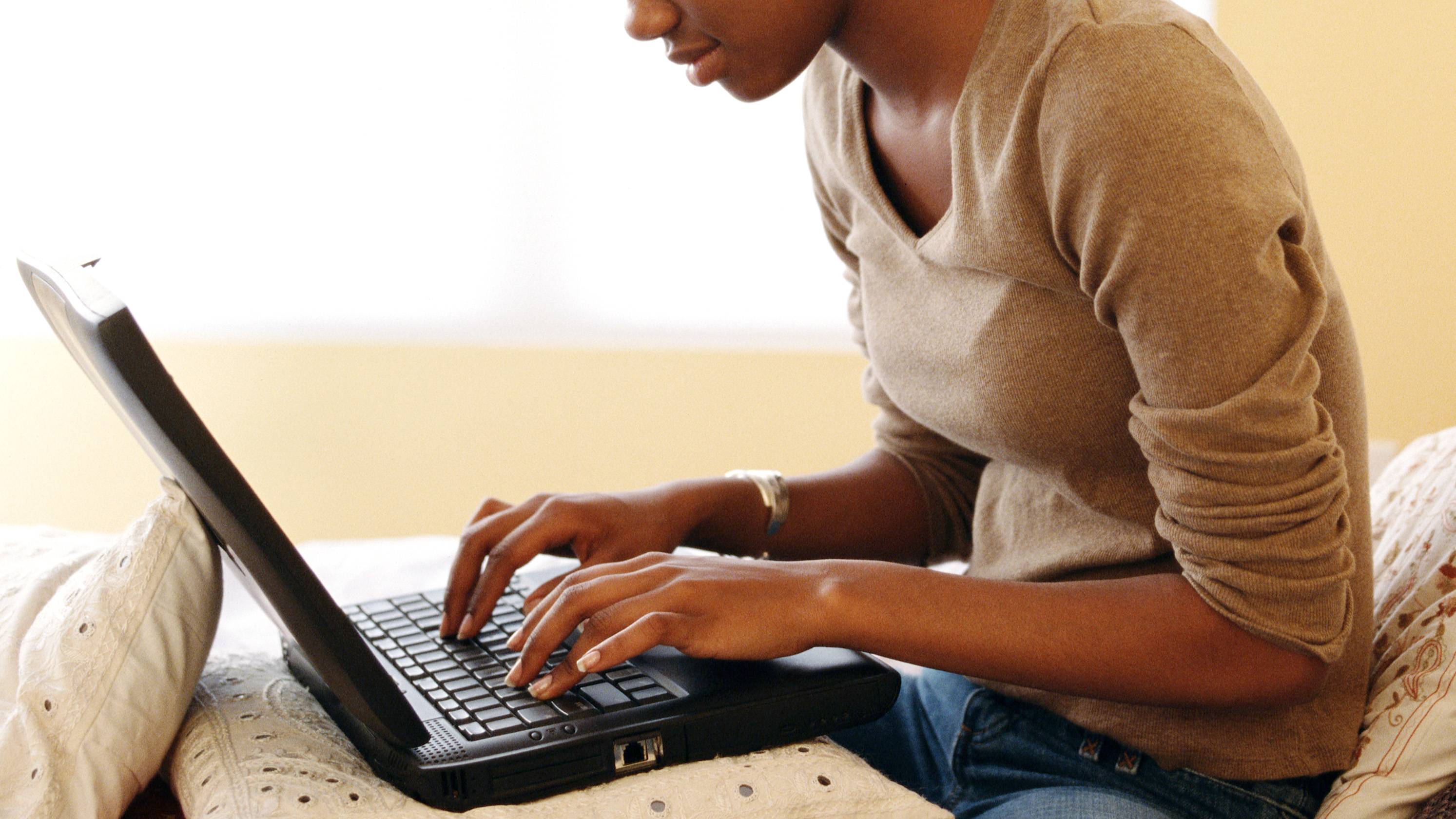 young lady working on her laptop in bed