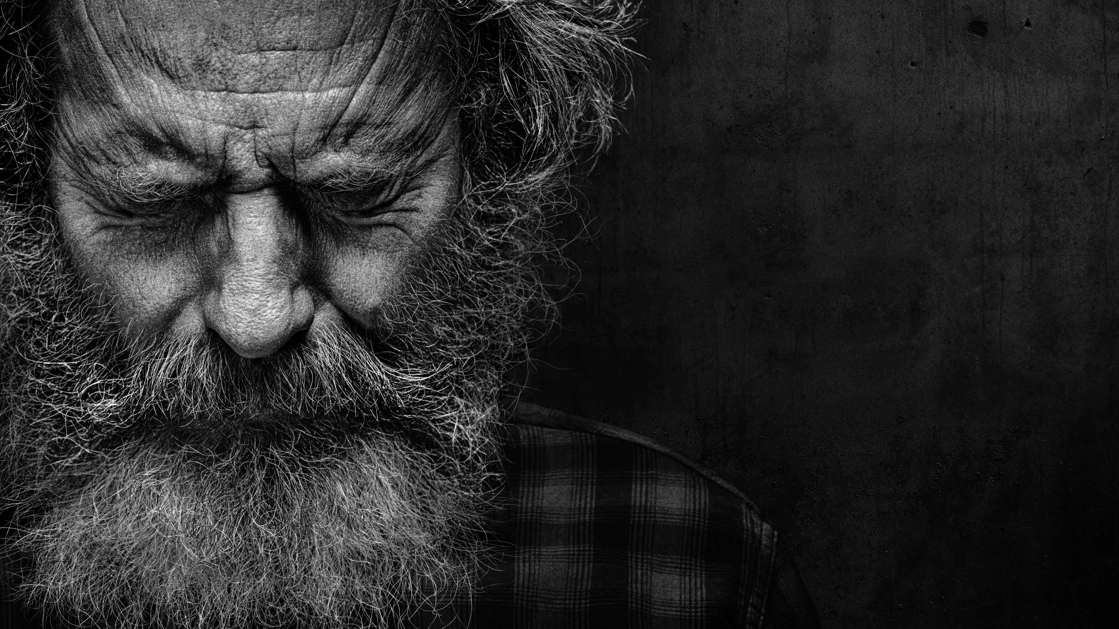 A black-and-white close-up of Bryan Cranston as Judge Michael Desiato, wearing a heavy beard and a pained expression.