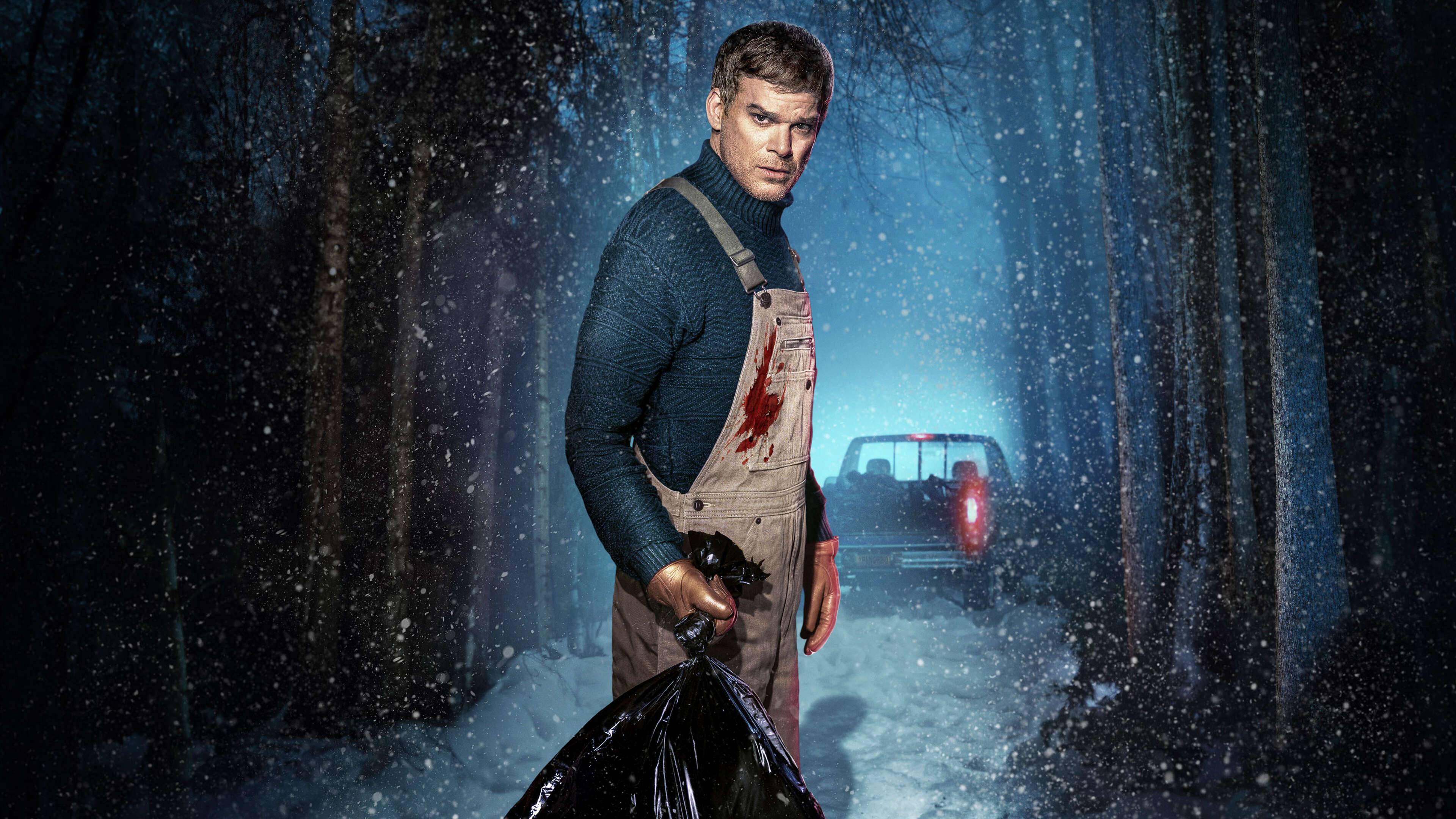 Michael C. Hall as Dexter Morgan standing in a snowy forest, wearing bloody overalls and holding a suspicious garbage bag.